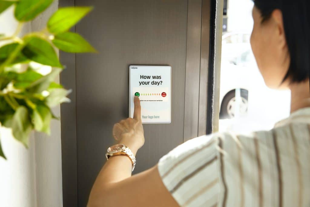 Woman giving feedback on her day via a mobile device hung on a door